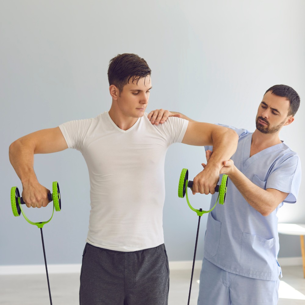 Physical therapist helping a young man lift resistance wheels