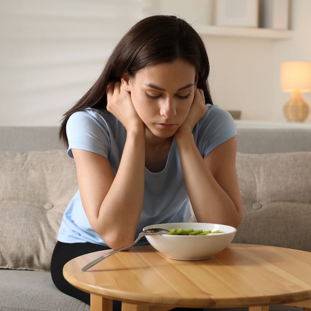 Upset woman stares at untouched salad bowl
