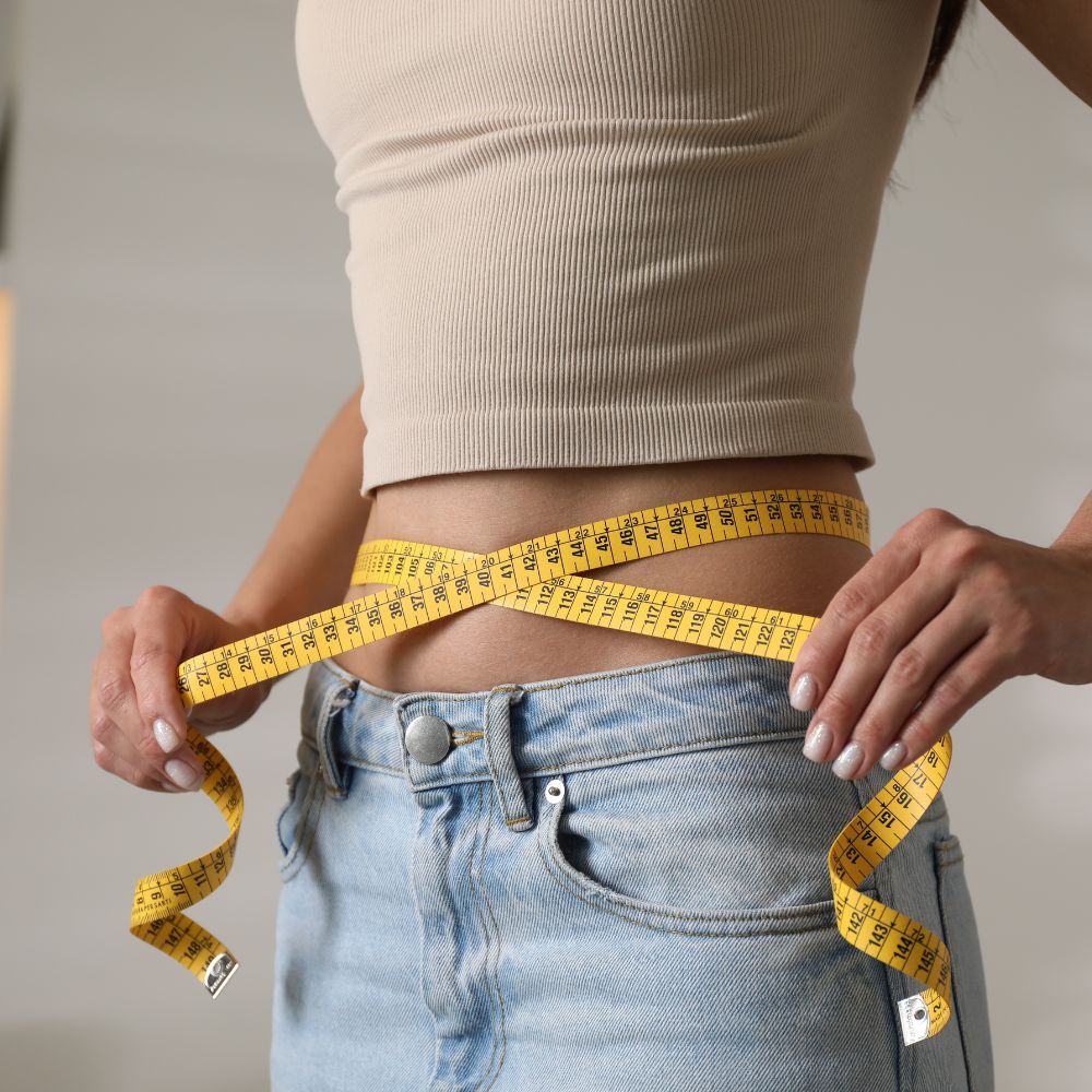 Closeup of woman measuring waist with tape