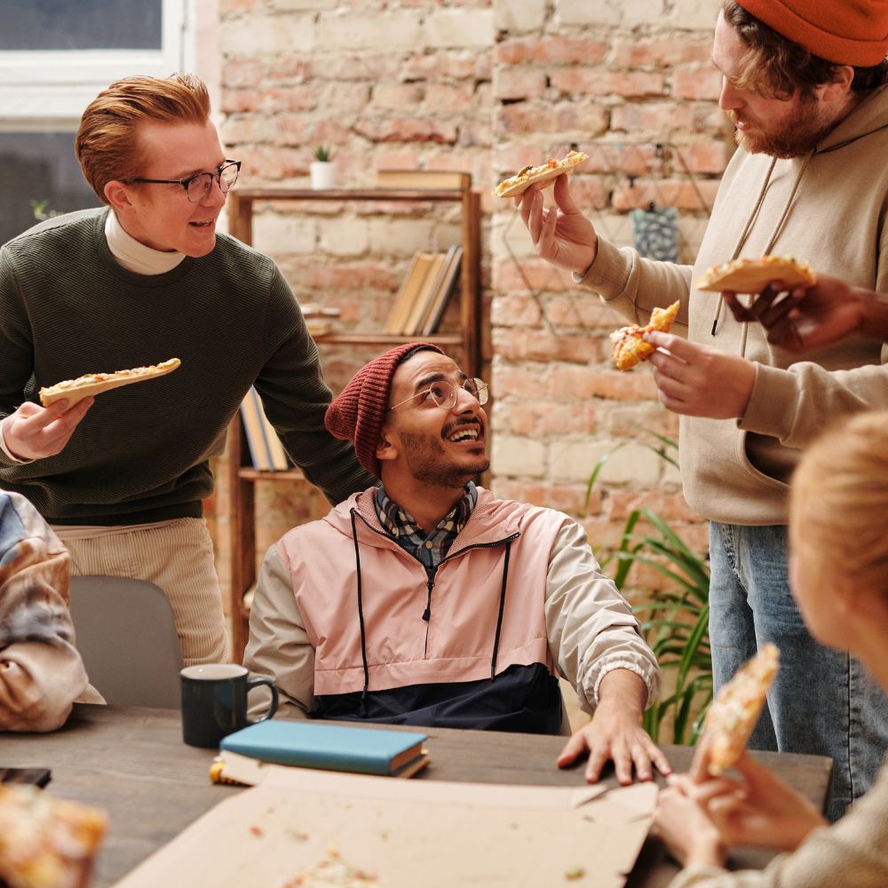 Students sharing pizza and laughing in dorm setting