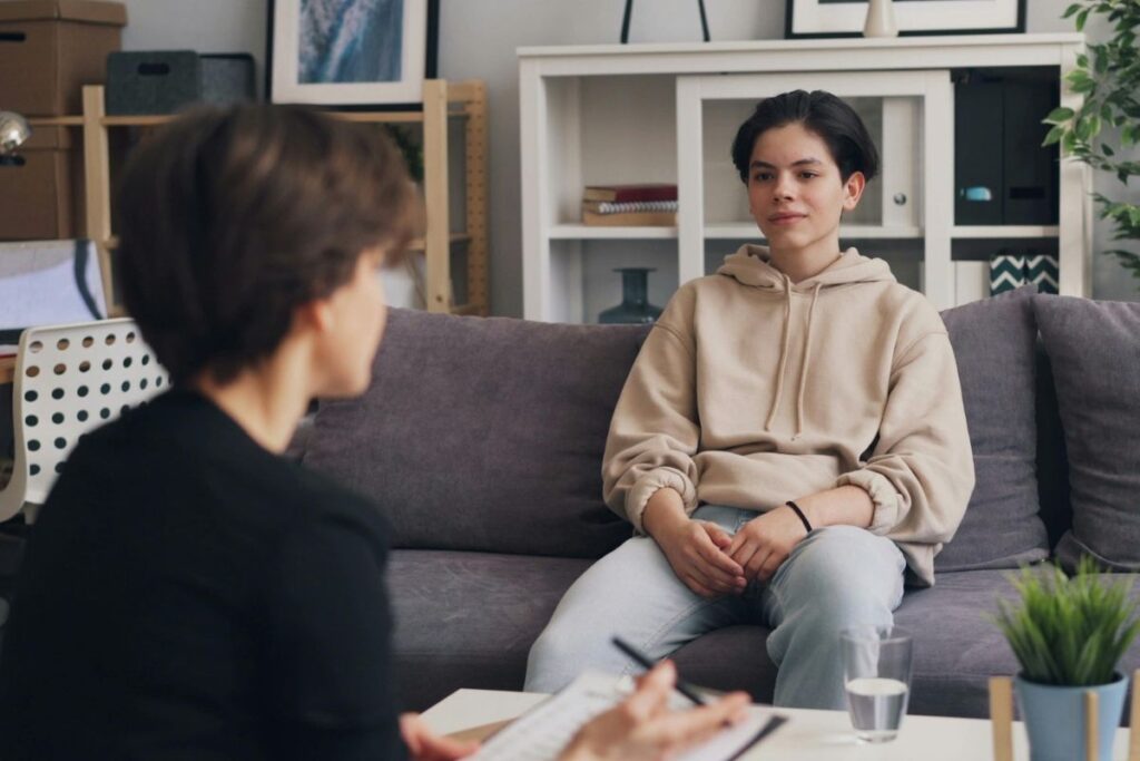 Teen sitting in a therapy session and engaging in conversation with a therapist