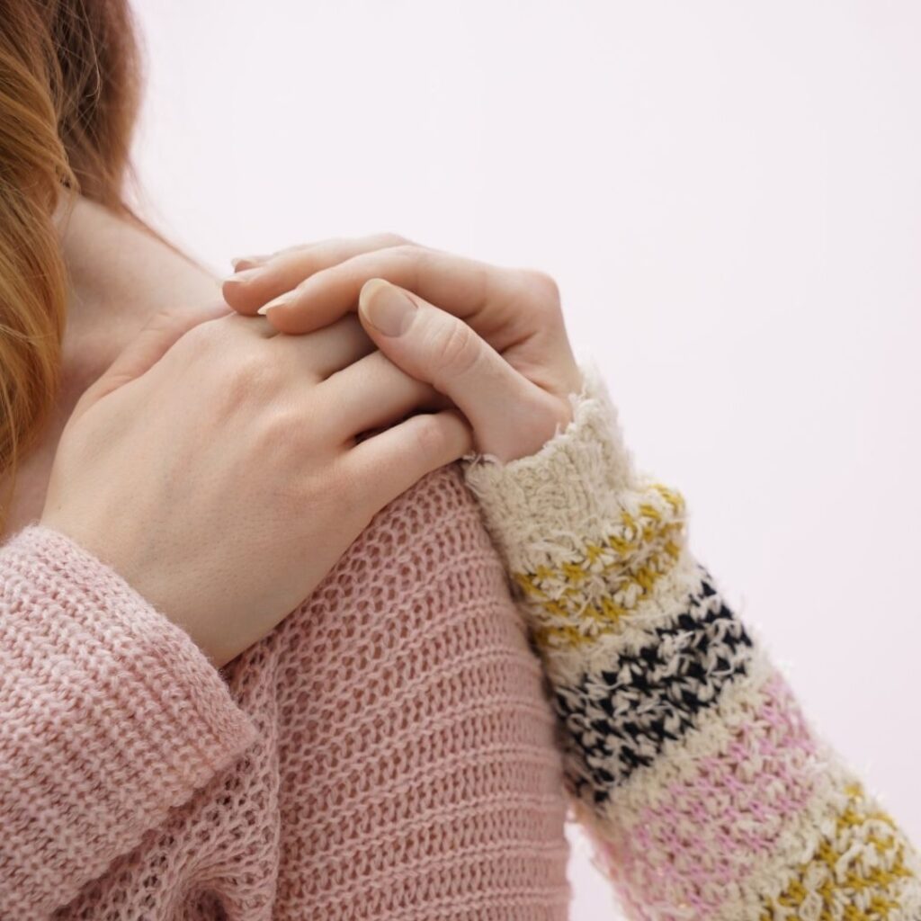 A comforting hand gently rests on a woman’s shoulder, offering support and compassion.