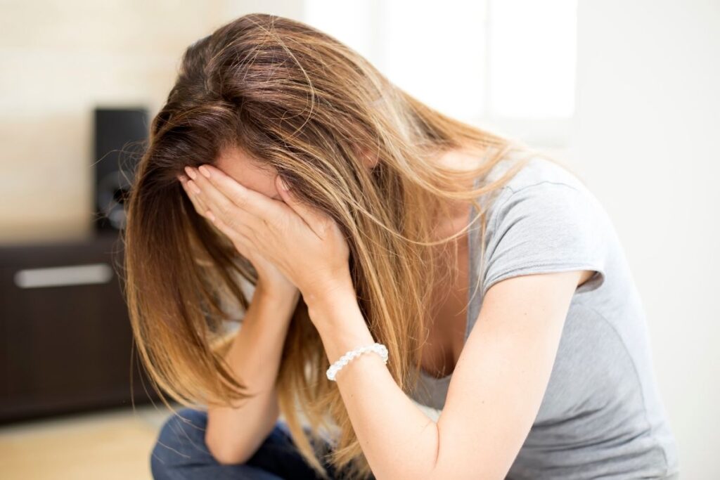 A distressed woman sitting with her head in her hands