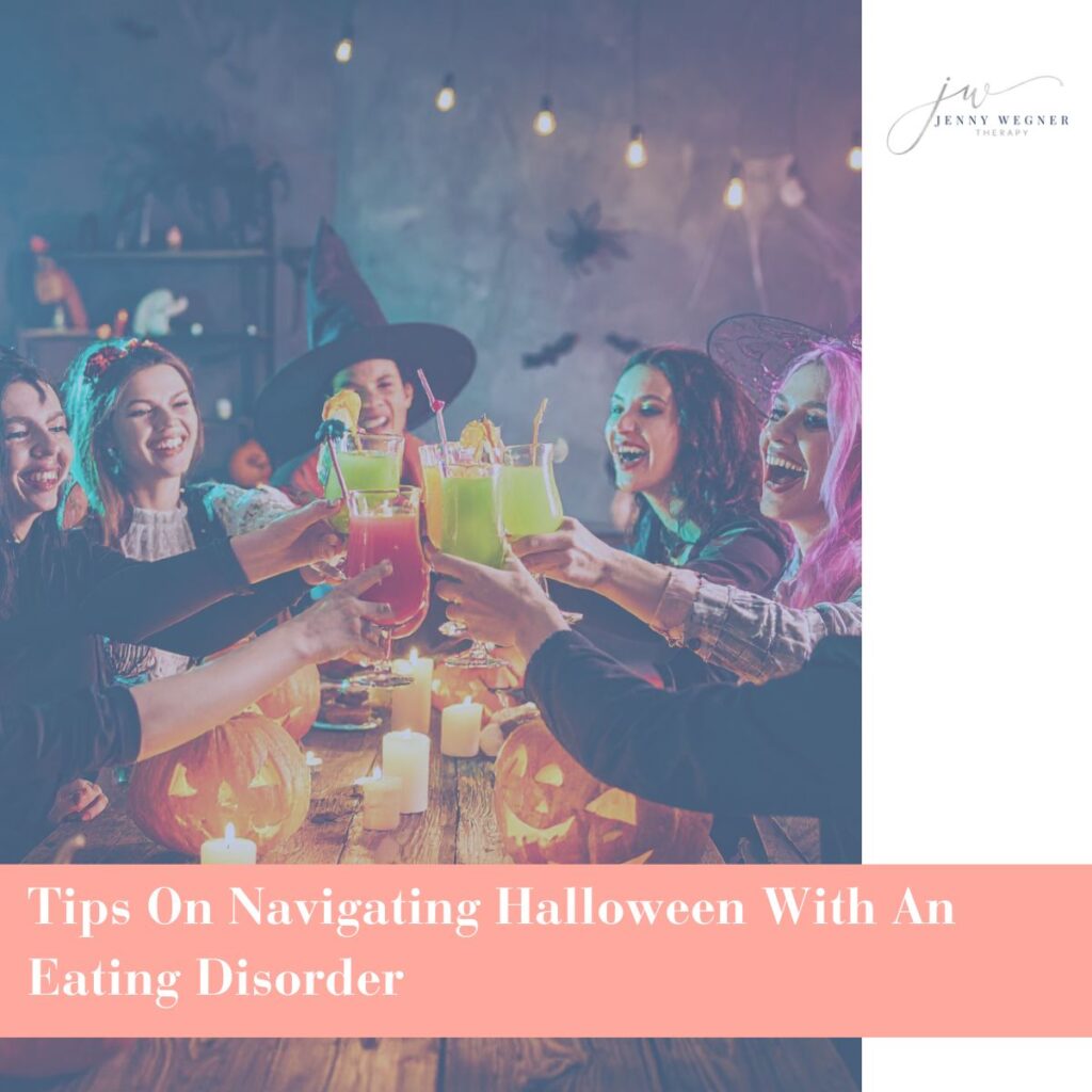 Group of friends in Halloween costumes raising colorful drinks over a table decorated with pumpkins and candles